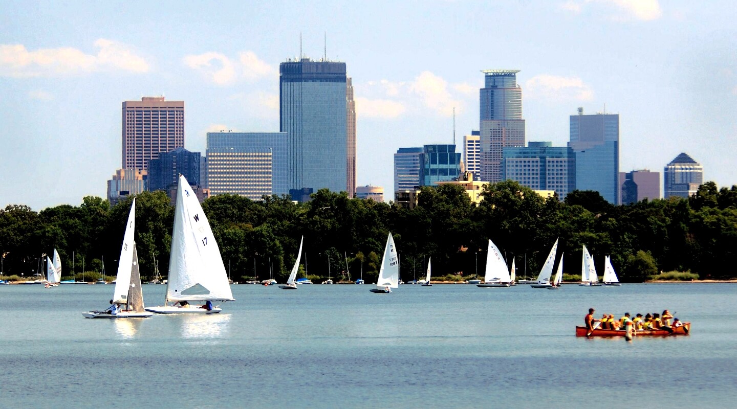 the minneapolis skyline from lake calhoun with sailboats on the lake